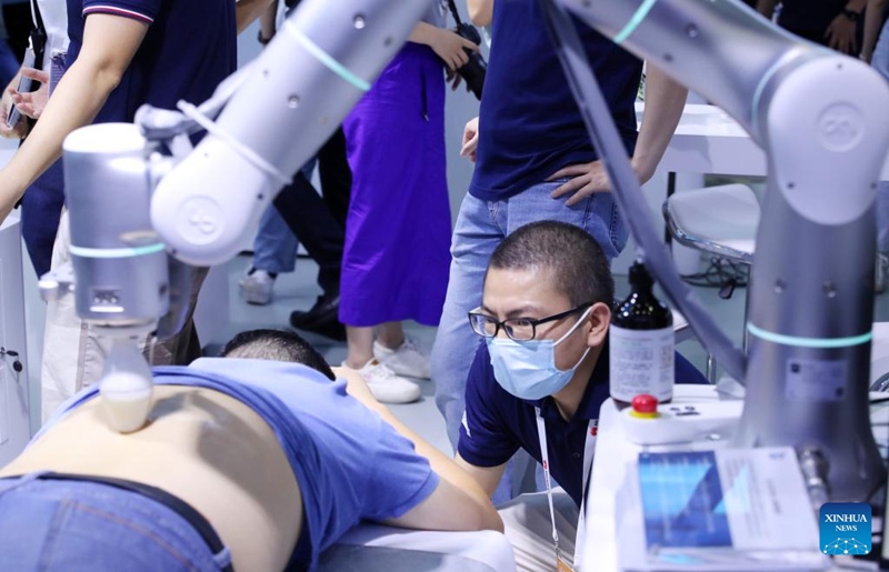 Mshiriki akipata hisia za masaji inayofanywa na roboti ya kufanyia masaji kwenye maonesho ya Mkutano wa Dunia wa Teknolojia za Akili Bandia Mwaka 2022 (WAIC) huko Shanghai, Mashariki mwa China, Septemba Mosi, 2022. Ukiwa na kaulimbiu ya "Muunganisho wa Kisasa, Multiverse Isiyo na Mwisho", Mkutano wa WAIC kwa mwaka huu umeanza Alhamisi huko Shanghai, China (Xinhua/Fang Zhe)