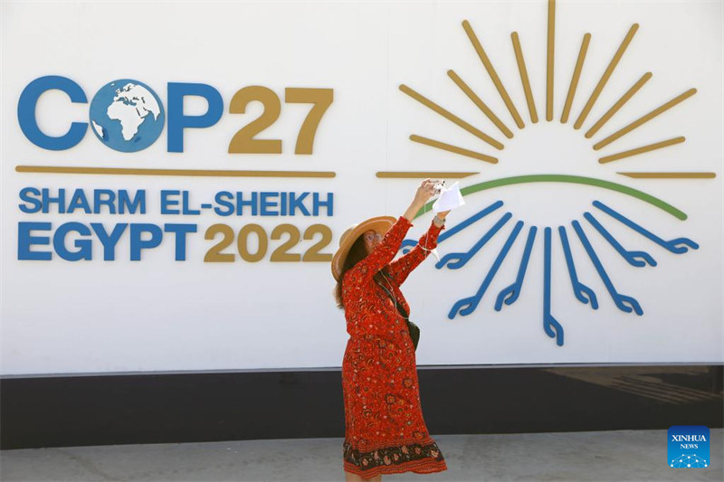 Mwanamke akipiga picha mbele ya bango linaloonesha Mkutano wa 27 wa Nchi washiriki wa Mkataba wa Mfumo wa Umoja wa Mataifa wa Mabadiliko ya Tabianchi (COP27) huko Sharm El-Sheikh, Misri, Novemba 6, 2022. Mkutano wa COP27 umefunguliwa Jumapili huko Misri, kwenye mji wa pwani wa Sharm El-Sheikh kwa matumaini ya kugeuza ahadi za ufadhili wa tabianchi duniani kuwa vitendo. (Xinhua/Sui Xiankai)