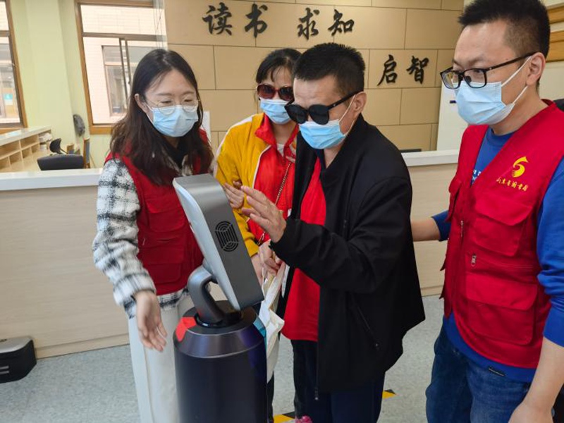 Msomaji mwenye matatizo ya kuona (wa pili kulia) akijaribu mwongozo wa roboti kwenye maktaba ya kidijitali ya Jinan, Mkoa wa Shandong， China, Oktoba 14, 2022. (Xinhua/Yuan Min)
