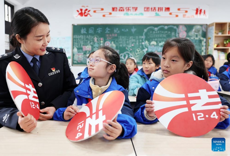 Afisa wa polisi akielezea Katiba ya Nchi ya Jamhuri ya Watu wa China kwa wanafunzi wa shule mjini Taizhou katika Mkoa wa Jiangsu, Mashariki mwa China, Desemba 4, 2023. (Picha na Tang Dehong/Xinhua)