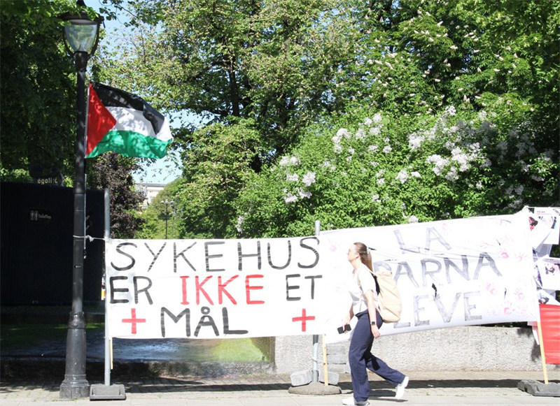 Mtu akipita mbele ya bendera ya Palestina huko Oslo, mji mkuu wa Norway, Mei 22, 2024. (Picha na Chen Yaqin/Xinhua)