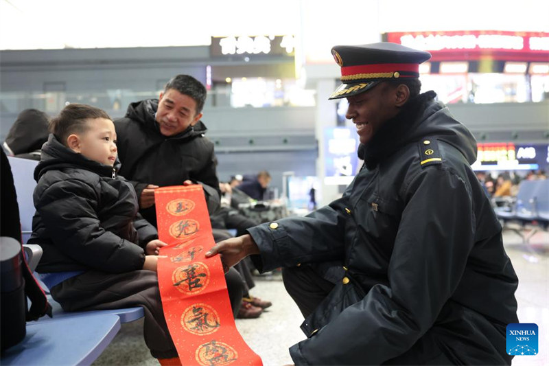 Wanafunzi wa kigeni?wawa watu wa kujitolea wa Stesheni ya Treni ya Lanzhou katika pilika za kuwahudumia?wasifiri wakati wa Mwaka Mpya wa Jadi wa China