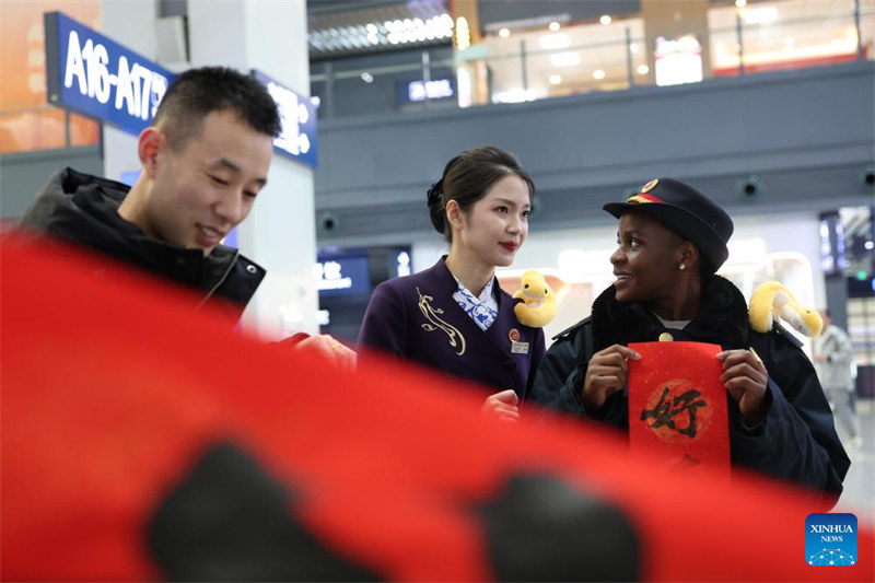 Wanafunzi wa kigeni?wawa watu wa kujitolea wa Stesheni ya Treni ya Lanzhou katika pilika za kuwahudumia?wasifiri wakati wa Mwaka Mpya wa Jadi wa China