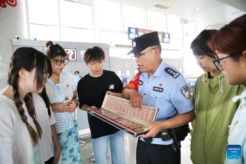Ofisa wa polisi akielezea ujuzi kuhusu kupambana na dawa za kulevya kwa abiria kwenye stesheni ya treni mjini Lianyungang, Mkoa wa Jiangsu, mashariki mwa China, Juni 25, 2025. (Picha na Wang Chun/Xinhua)