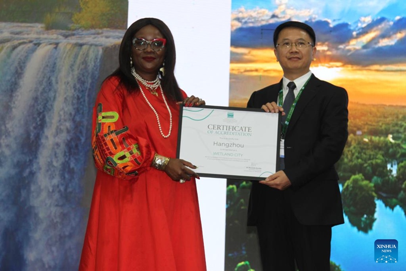 Musonda Mumba (kushoto), katibu mkuu wa Mkataba wa Ardhioevu akikabidhi cheti cha mji wa ardhioevu wa kimataifa   kwa mwakilishi kutoka Hangzhou, Mkoa wa Zhejiang, mashariki mwa China, mjini Victoria Falls, Zimbabwe, Julai 24, 2025. (Xinhua/Tafara Mugwara)
