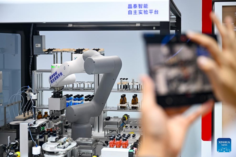Mtembeleaji maonyesho akipiga picha za bidhaa kwenye banda la XtalPi kwenye Mkutano wa AI Duniani 2025 huko Shanghai, mashariki mwa China, Julai 27, 2025. (Xinhua/Chen Haoming)